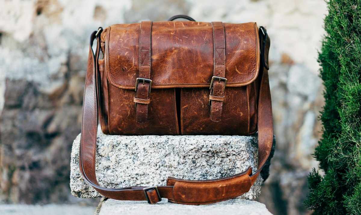 Brown leather messenger bag resting on stone